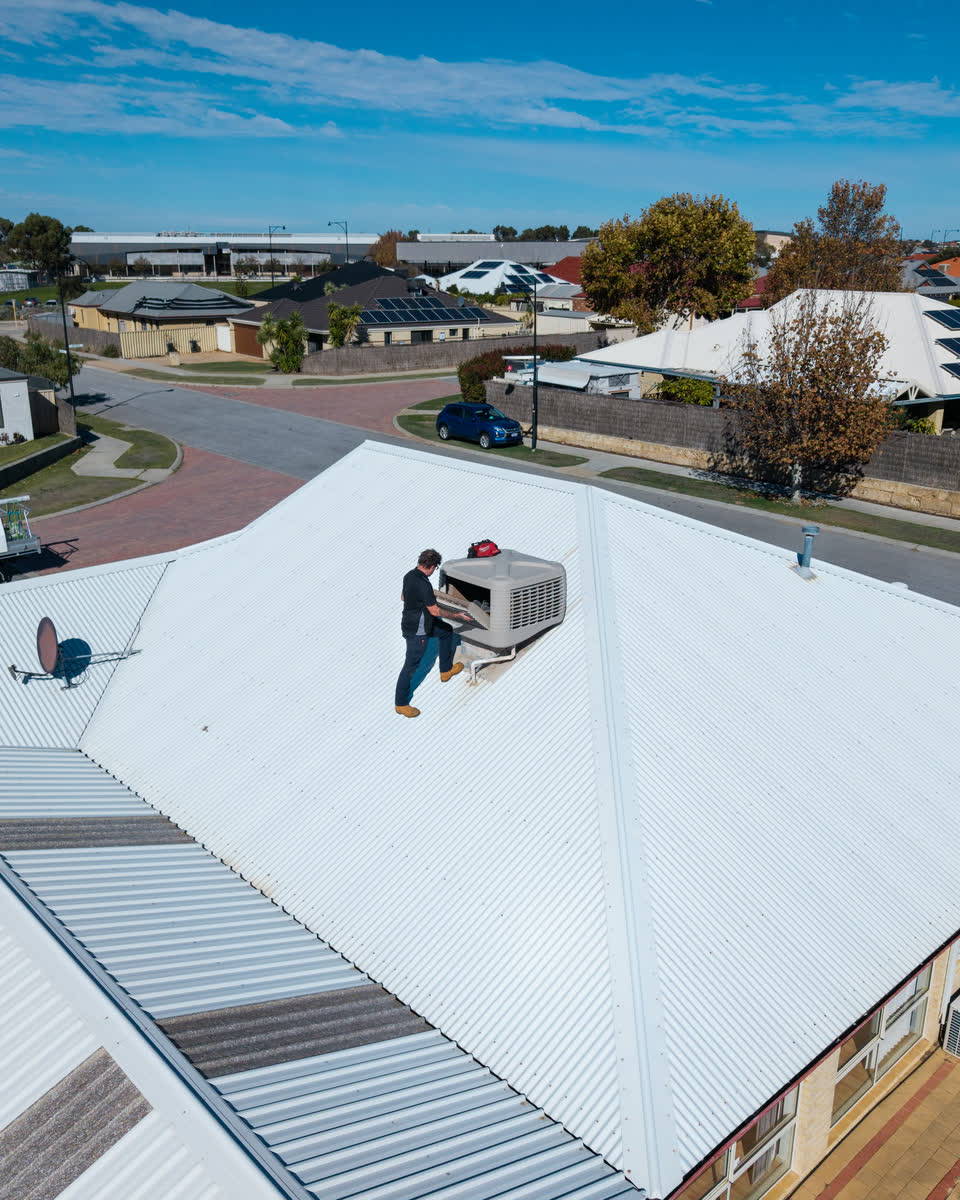 Drone view of a Westplumb technician at an evap unit on a roof