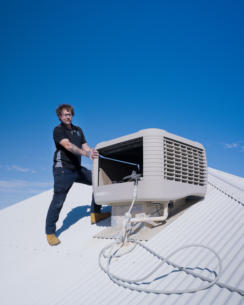 A Westplumb technician at an evap unit under a blue sky