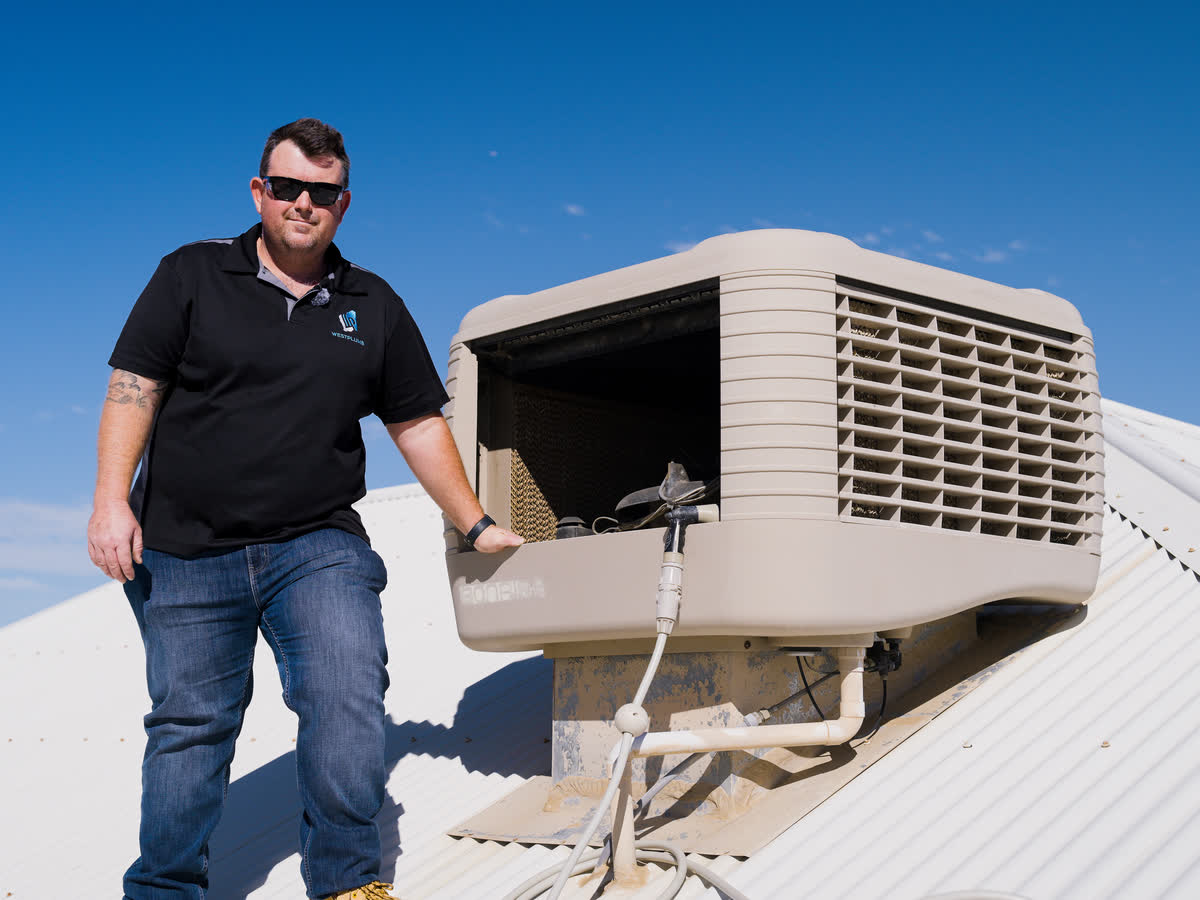 Brent beside an evaporative air conditioner on a roof