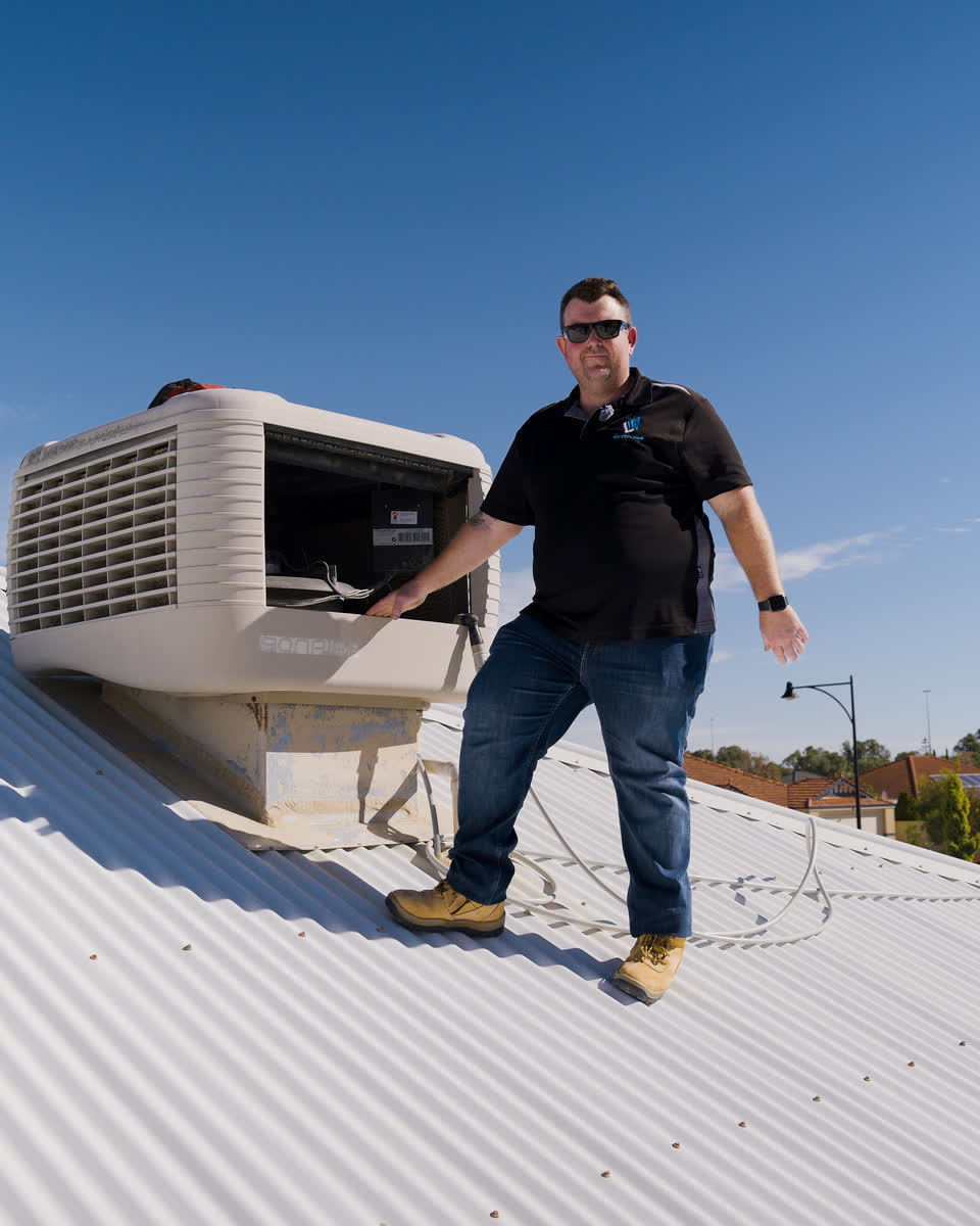 Brent beside an evap unit on a white roof