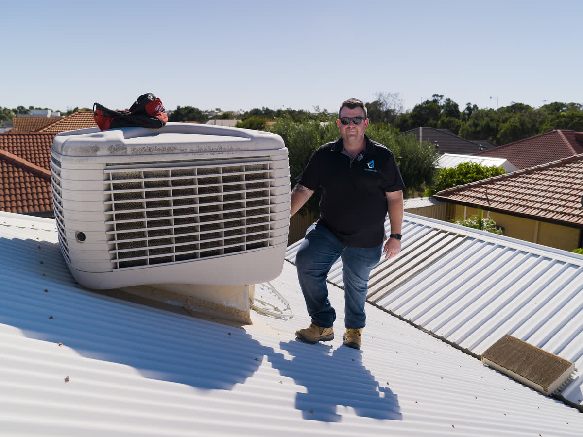 Brent beside an evaporative air conditioner on a roof