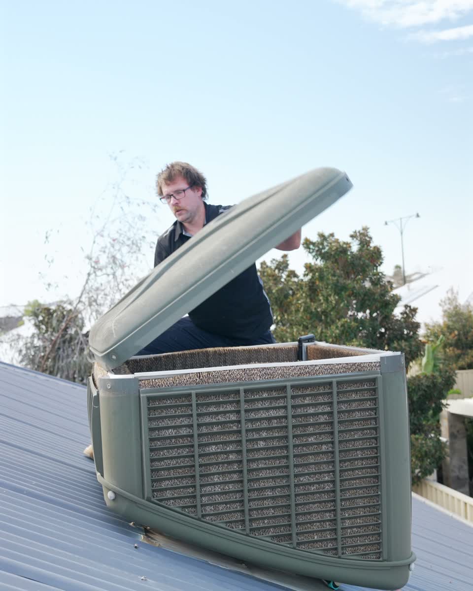 A Westplumb technician lifting the lid of an evaporative air conditioner