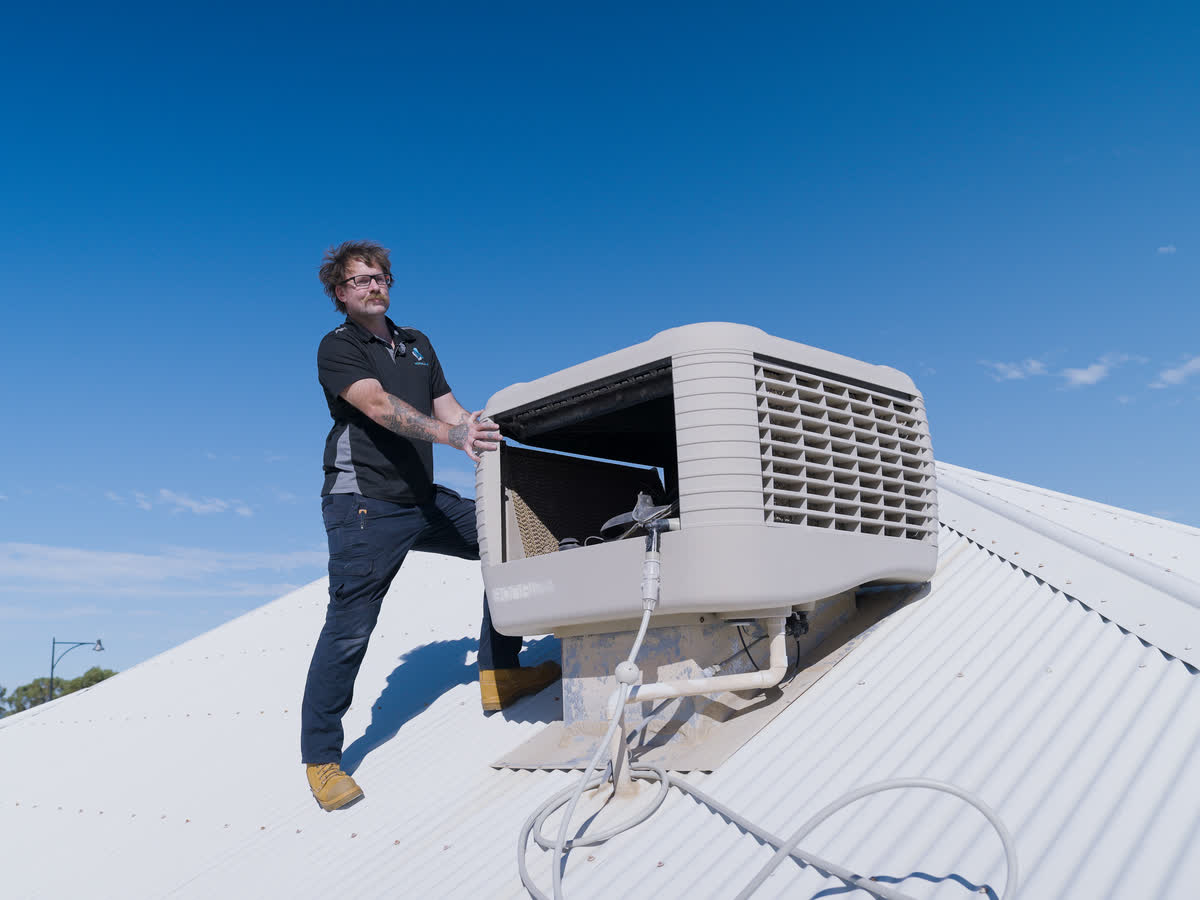 Brent beside an evap unit on a tiled roof